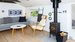 Un salon moderne avec un canapé, une table basse ronde, un fauteuil et un poêle à bois.