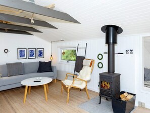 A modern living room with a sofa, a round coffee table, a chair, and a wood-burning stove. - 6 Person Holiday Home in Fjerritslev (Fjerritslev)