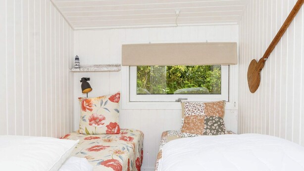 Une chambre avec deux lits, une fenêtre donnant sur un paysage verdoyant, une lampe et une guitare accrochée au mur.