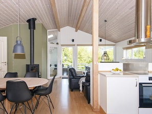 A modern kitchen with a built-in stove, dining area with chairs, and a view of the outdoors. - 10 Person Holiday Home in Juelsminde-by Traum (Horsens)