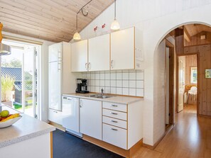 A modern kitchen with white cabinets, a built-in dishwasher, and a coffee maker.