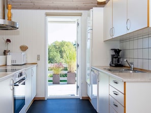 A modern kitchen with white cabinets, a coffee maker, and a view of the outdoors. - 10 Person Holiday Home in Juelsminde-by Traum (Horsens)