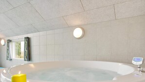 A modern bathroom with a freestanding bathtub, two lit candles, and a digital thermometer on the wall. - 5 Star Holiday Home in Sydals (Sydals)