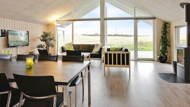Ein modernes Interieur mit Essbereich, Sitzgelegenheiten und einem großen Fenster mit Blick auf ein Feld.