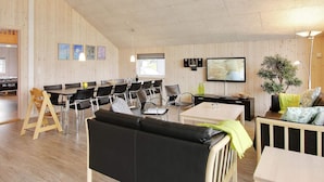 Ein Zimmer mit Essbereich, einer Couch, einem Fernseher und einer Pflanze.