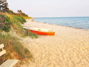 Una spiaggia sabbiosa con una barca rossa e una panchina di legno.