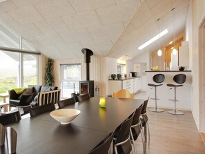 A modern kitchen with a central island, a dining area with a long table and chairs, and a cozy seating area with a sofa and chairs. - 14 Person Holiday Home in Sydals (Sydals)