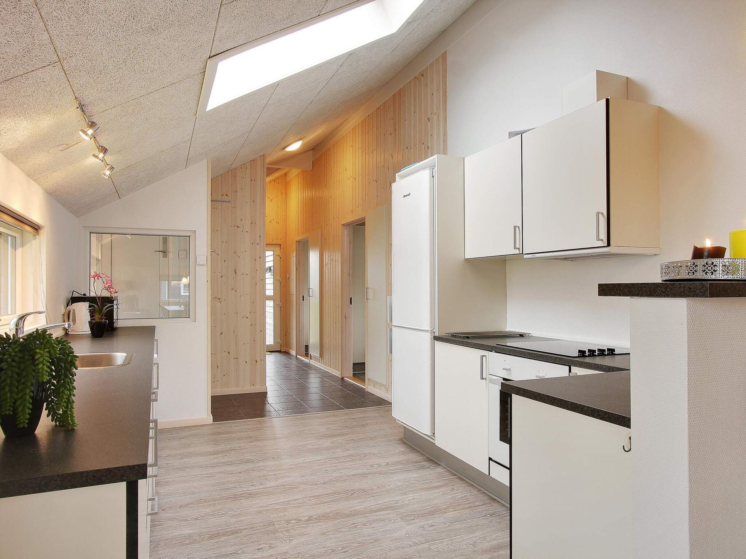 A modern kitchen with white cabinets, a black countertop, and a skylight.