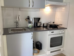 Una cocina compacta con fregadero, estufa, horno y tostadora.