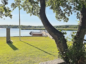 A grassy area with a dock and boats, a stone pillar, and a tree. - 4 Star Holiday Home in Solvesborg (Sölvesborg)