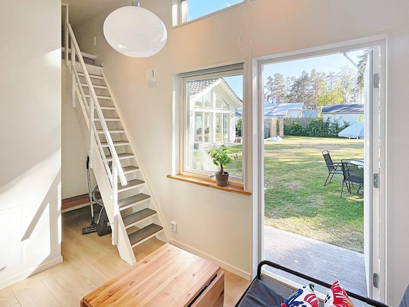 A staircase leading to a second floor, a window with a view of a backyard, and a bench in the foreground.