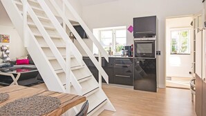 A modern kitchen with a built-in oven and a dining area with a wooden table and chairs.