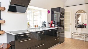 A modern kitchen with dark cabinetry, a built-in oven, and a large window providing natural light.