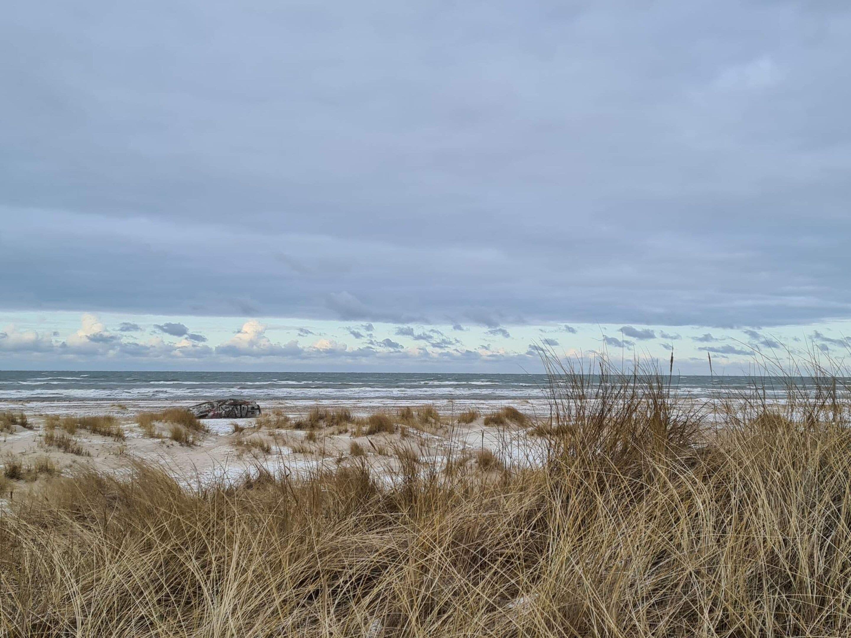 Una playa con dunas de arena y vegetación escasa.