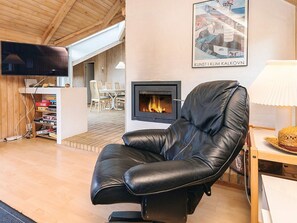 Una sala acogedora con un sillón de cuero, chimenea, televisor y comedor.
