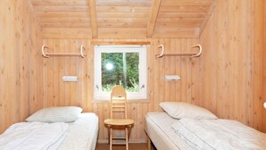 A room with two beds, a window, and a chair.