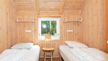 A room with two beds, a window, and a chair.