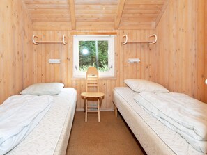 Una habitación con dos camas, una ventana y una silla.