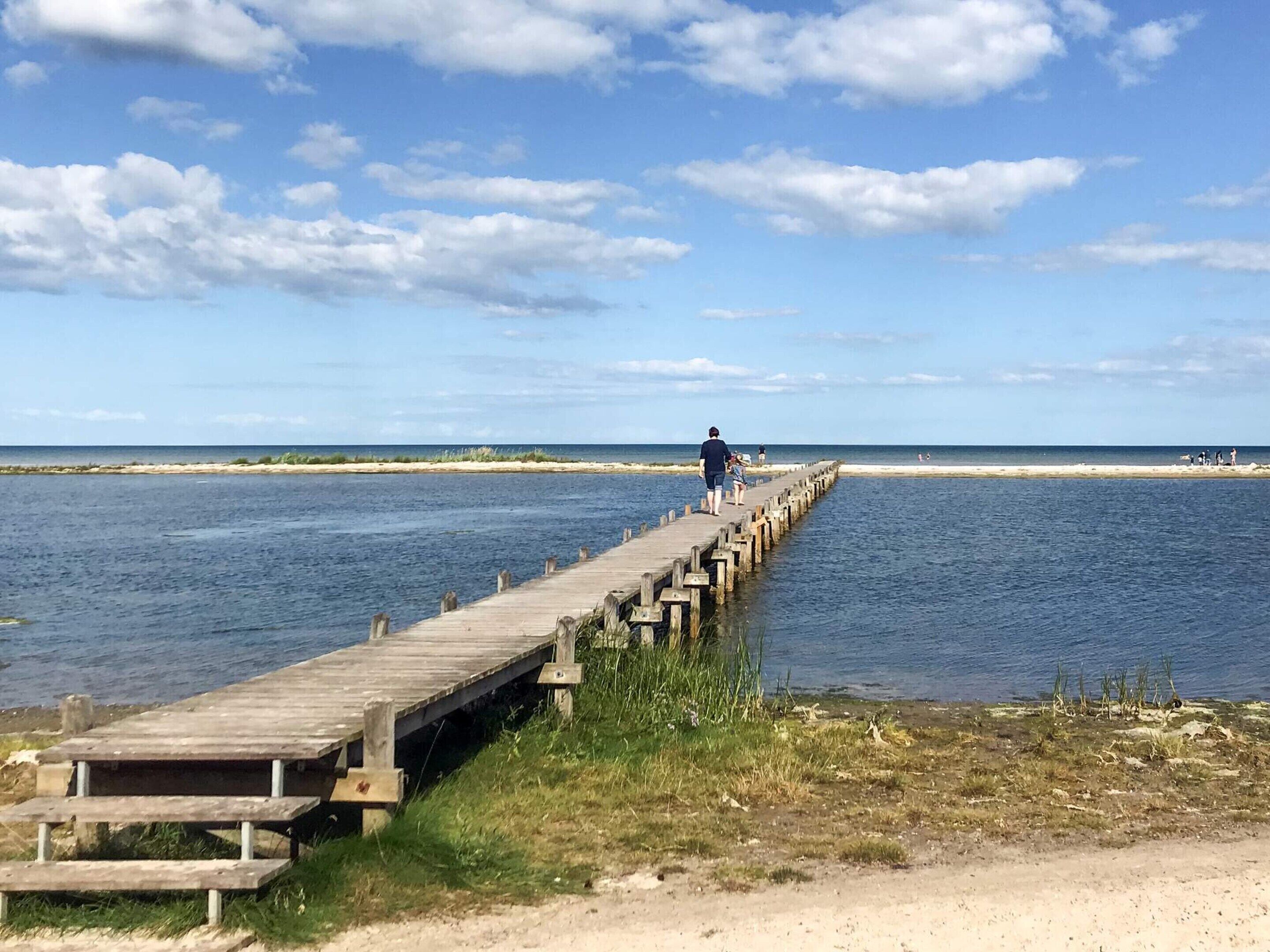 A wooden pier extending into a body of water with a clear sky above.