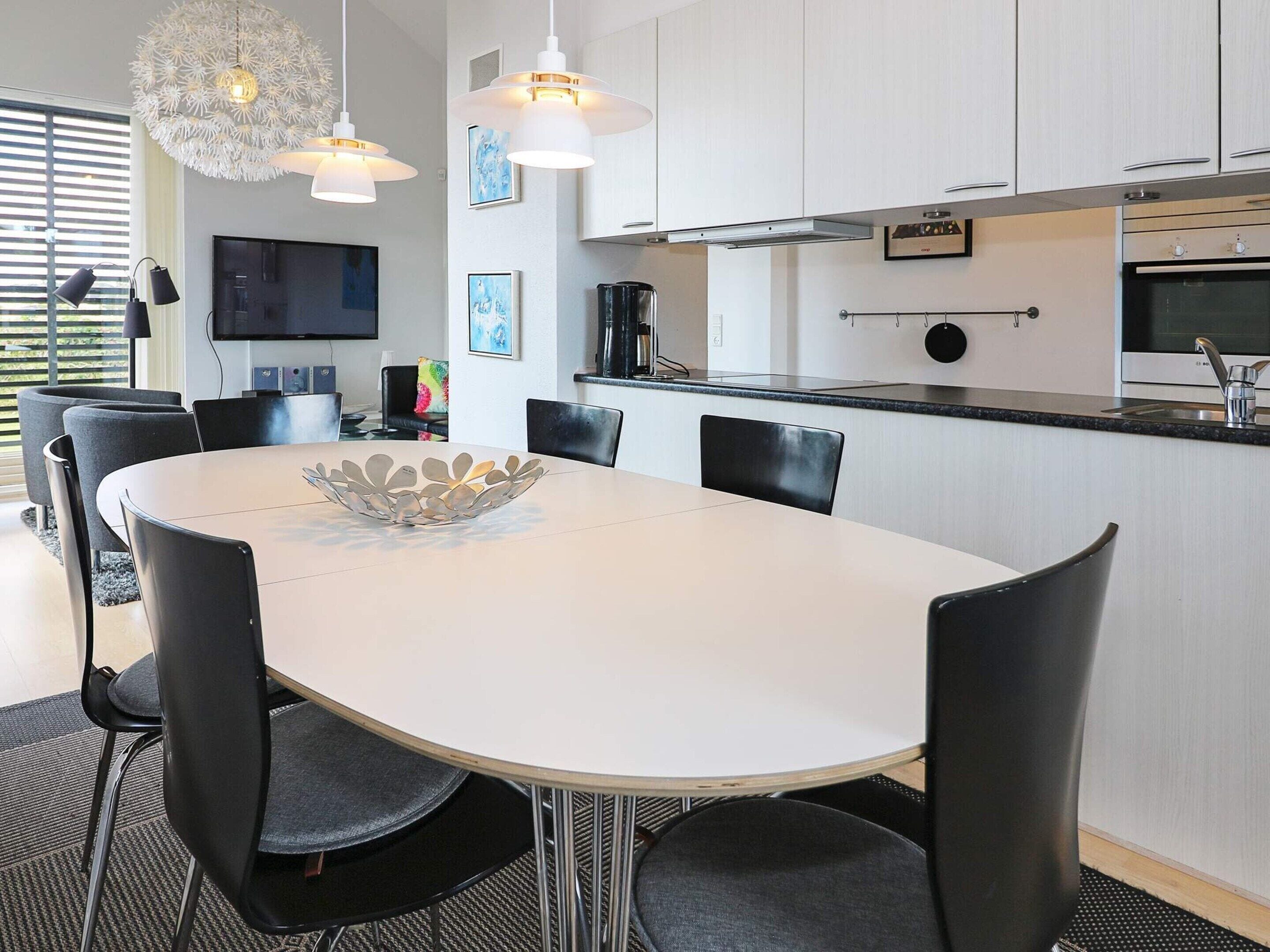 A modern kitchen with white cabinets, a black countertop, and stainless steel appliances.