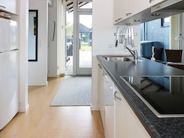 Una cocina moderna con estufa integrada, pileta de acero inoxidable y espacio para cuchillos.