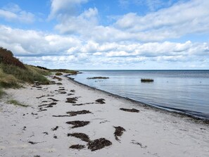 A beach with a sandy shore and calm water. - 6 Person Holiday Home in Hadsund (Hadsund)