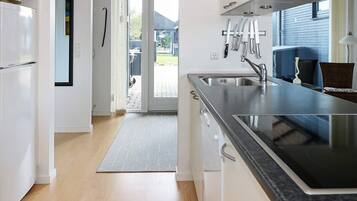 A modern kitchen with a built-in stove, a stainless steel sink, and a window overlooking a garden.