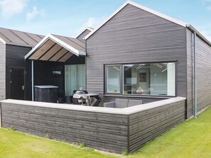 A modern house with a sloped roof, a large window, and a patio area with outdoor furniture. - 6 Person Holiday Home in Hadsund (Hadsund)