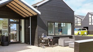 A modern house with a large window, a barbecue setup, and a yellow car parked outside. - 6 Person Holiday Home in Hadsund (Hadsund)