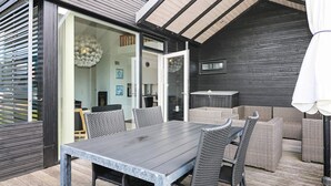 An outdoor dining area with a table and chairs, a wicker sofa, and a ceiling with wooden beams. - 6 Person Holiday Home in Hadsund (Hadsund)
