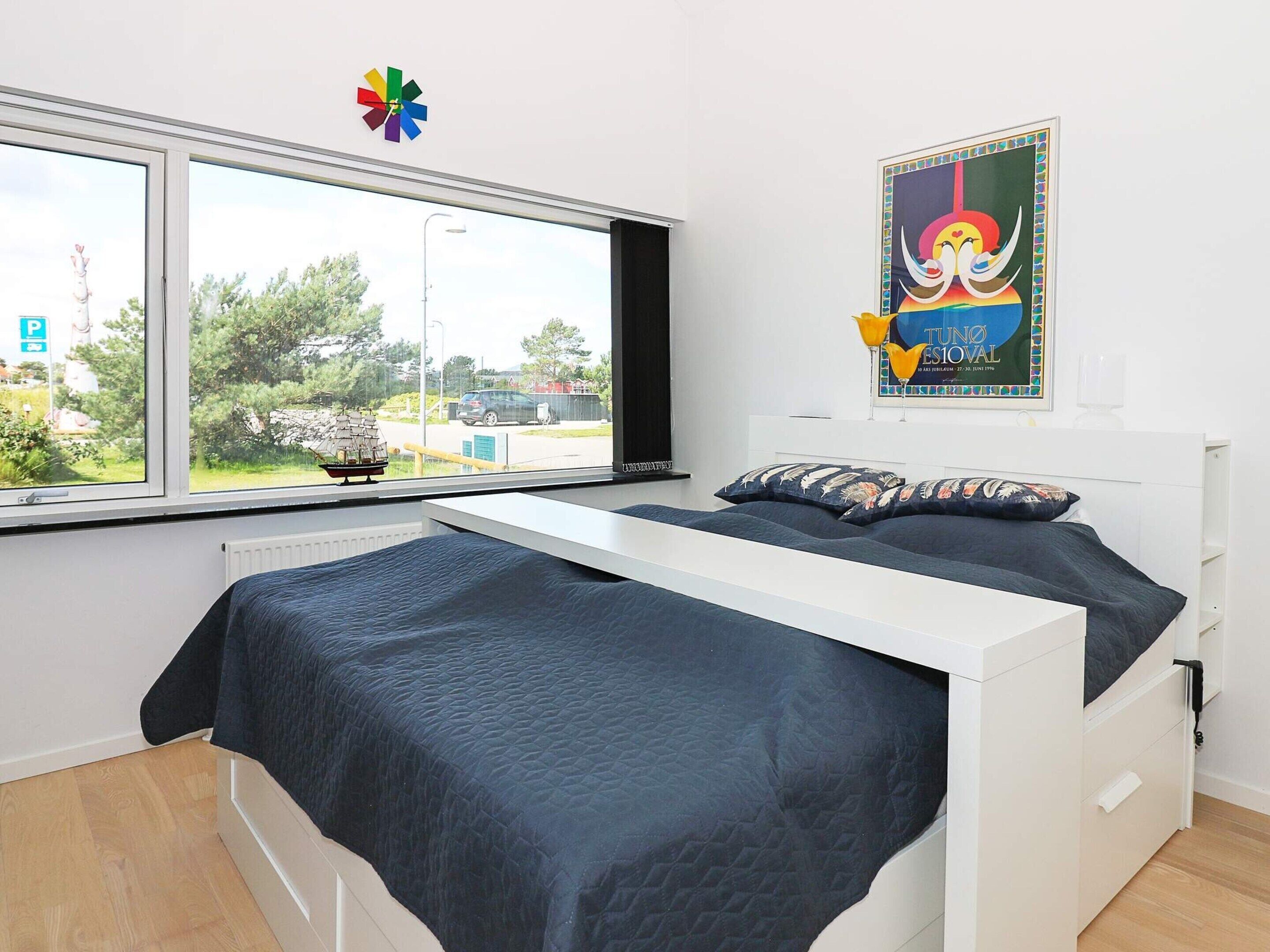 A bedroom with a bed, a window, and a poster on the wall.