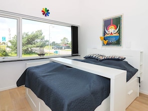 A bedroom with a bed, a window, and a poster on the wall. - 6 Person Holiday Home in Hadsund (Hadsund)