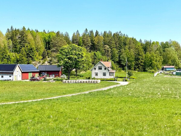 A rural landscape with a red barn, a white house, and a large tree in the foreground. - 4 Person Holiday Home in Fargelanda-by Traum (Färgelanda)
