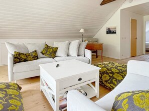 Un salon chaleureux avec un canapé blanc, une table basse et des coussins à motifs.