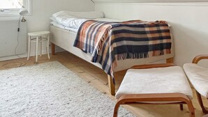 A small, single-bed room with a sloped ceiling, a white wall, a small stool, and a bench. - 4 Star Holiday Home in Branno (Branno)