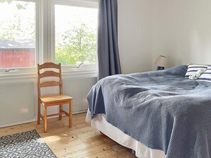 A bedroom with a bed, a chair, a window, and a lamp. - 4 Star Holiday Home in Branno (Branno)