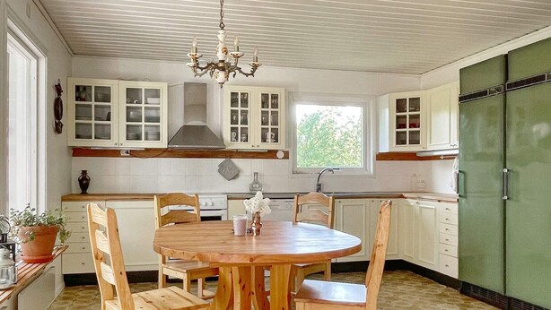 A kitchen with a round wooden table, white cabinets, and a green refrigerator. - 4 Star Holiday Home in Branno (Branno)