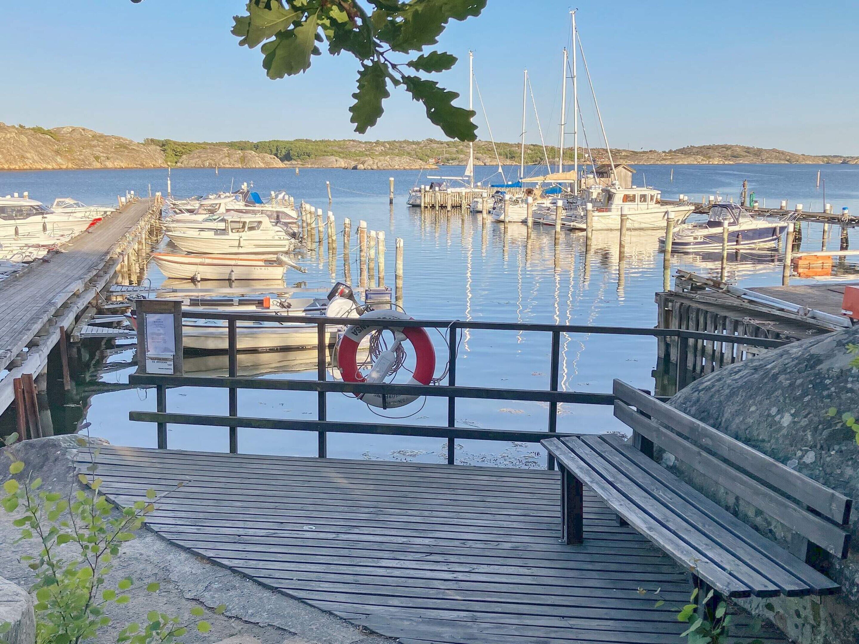A wooden dock leading to a marina with boats docked.