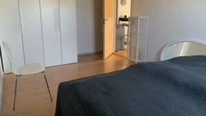 A bedroom with a bed, a chair, and a wardrobe.