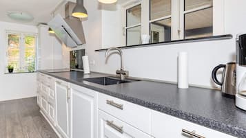 A modern kitchen with white cabinetry, a granite countertop, and pendant lighting.