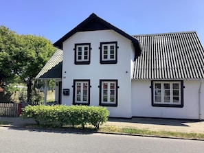 A two-story white building with black trim and a sloped roof.