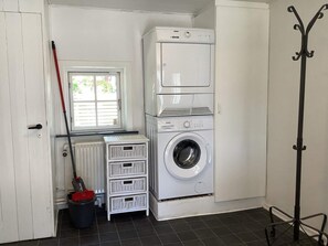 A laundry room with a front-loading washing machine, a drying machine, a mop, and a bucket. - 6 Person Holiday Home in Thisted (Thisted)