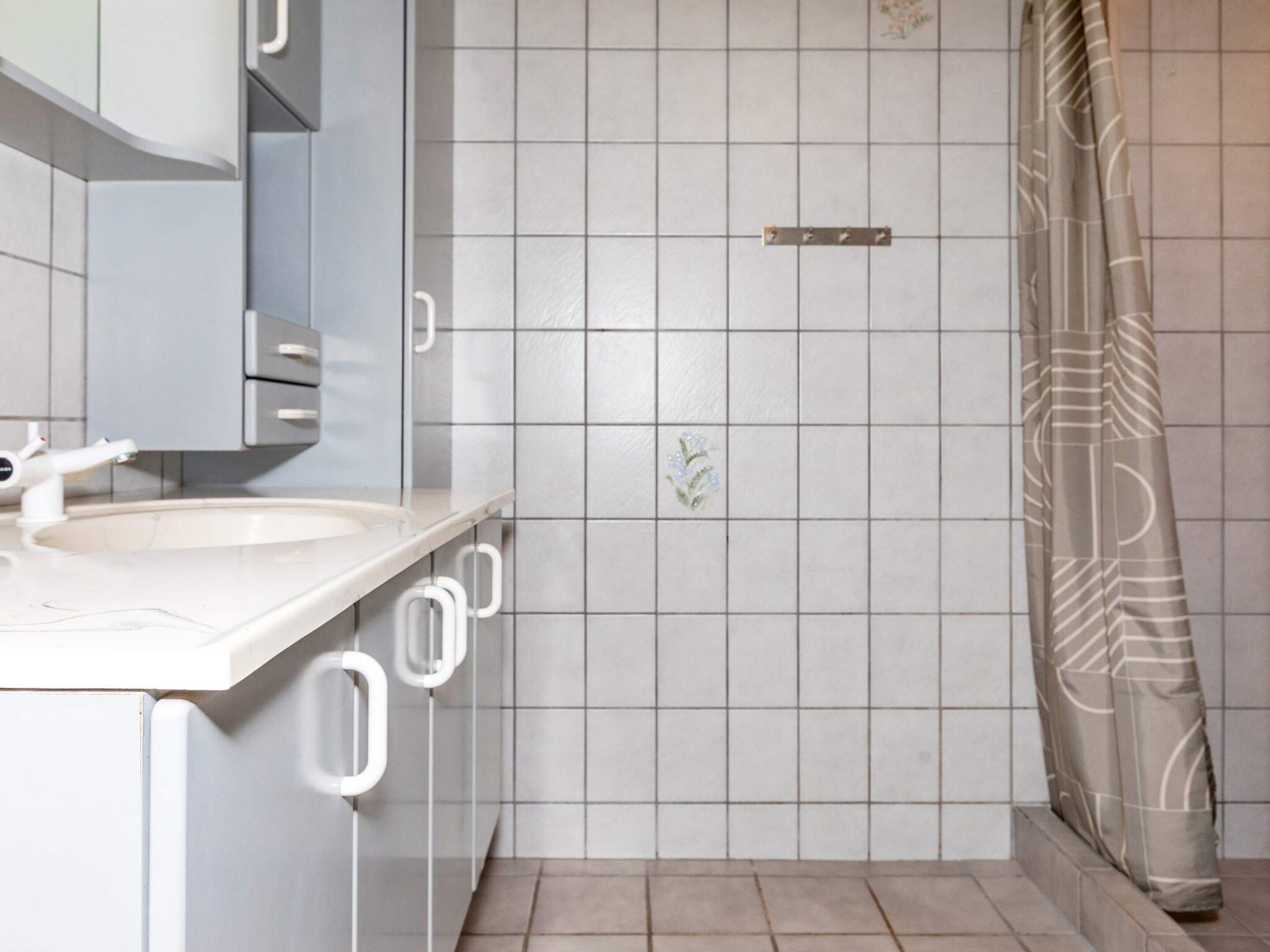 A bathroom with a white sink, mirror, and shower curtain.