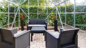 Ein Gewächshaus mit Glasdach, einem Tisch in der Mitte und zwei Stühlen.