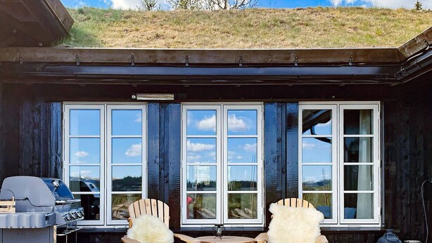 A covered patio with two Adirondack chairs, a grill, and a table. - 10 Person Holiday Home in Nesbyen-by Traum (Nes)
