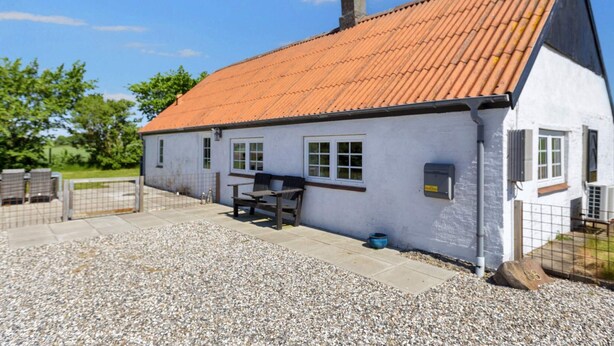 A single-story building with a sloped roof, a gravel driveway, and a fenced outdoor area. - 5 Person Holiday Home in Karby (Øster Assels)