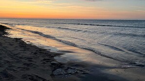 A beach with waves gently lapping onto the shore, under a clear sky. - 5 Person Holiday Home in Karby (Øster Assels)