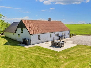A white building with a red roof, a patio with outdoor furniture, and a fenced yard. - 5 Person Holiday Home in Karby (Øster Assels)