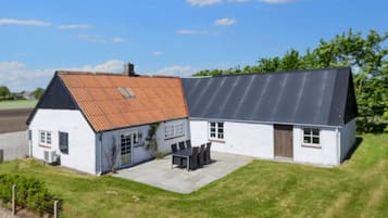 Een huis met twee verdiepingen, een pannendak, een omheinde tuin en een verharde oprit.