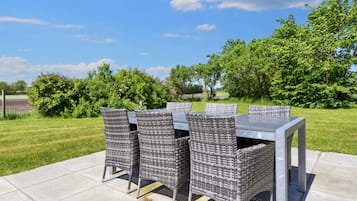 Een terras met een tafel en stoelen, omringd door planten en bomen.